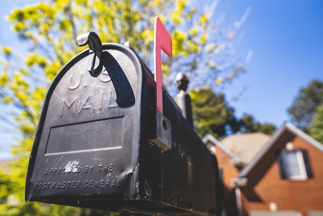 a black mailbox with red flag signing mail inside